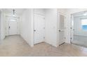 Bright hallway with neutral tile flooring, white walls, and doorways leading to various rooms in the home at 4203 San Rocco Way, Winter Haven, FL 33884