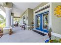 Charming covered porch featuring tiled flooring, white pillars, and stylish double door entry at 4540 Park Ave, Indian Lake Estates, FL 33855