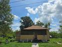 A charming home exterior showing a screened front porch under a sunny, partly cloudy sky at 4885 Cherry Dr, Mulberry, FL 33860