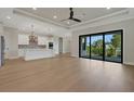 Open floorplan with hardwood flooring, white kitchen cabinets and stainless appliances, and a sliding glass door at 5390 Clubhouse Hills Ln, Lakeland, FL 33812