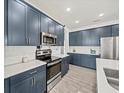 Modern kitchen features custom blue cabinets, stainless steel appliances and bright recessed lighting at 6520 Great Bear Dr, Lakeland, FL 33805