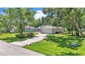 Aerial view of a single-story home with a long driveway, a well-maintained yard, and mature trees at 6735 Forestwood W Dr, Lakeland, FL 33811