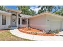 Inviting front entrance with a garden bed with flowering plants leading to a well-maintained gray house at 6735 Forestwood W Dr, Lakeland, FL 33811