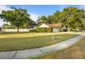 Landscaped front yard with green grass and mature trees surrounding a white single story home at 781 Bryson Loop, Lakeland, FL 33809