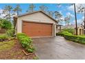 Exterior view of attached garage and driveway featuring manicured landscaping at 7952 Grand Pines Blvd, Lakeland, FL 33810