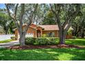 Brick home with well-maintained lawn and landscaping, framed by mature trees at 909 Lake Deeson Pt, Lakeland, FL 33805