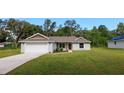 Charming single-story home with a two-car garage, landscaped yard, and a vibrant red front door at 10470 Sw 139Th Ct, Dunnellon, FL 34432