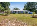 Charming single-story home featuring a metal roof, blue facade, and expansive front yard with garden at 120 Bolender Rd, Auburndale, FL 33823