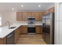 Modern kitchen featuring stainless steel appliances, wood cabinets, white countertops and stainless steel sink at 2206 Oldham Ct, Haines City, FL 33844