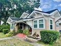 A charming home showcasing architectural details with a welcoming red porch, lush greenery, and sunlit facade at 236 E Seminole Ave, Lake Wales, FL 33853