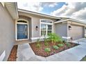 Close up of landscaped front entrance with a gray exterior, arched window and a blue front door at 4023 Tullamore Ln, Auburndale, FL 33823