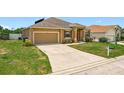 Home's front exterior featuring a two-car garage and landscaped front yard with healthy grass and shrubbery at 4041 Byrds Crossing Dr, Lakeland, FL 33812