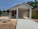 New construction, one story home with an orange front door and covered parking area at 629 W 9Th, Lakeland, FL 33805