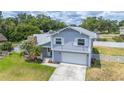 Two-story home with gray siding, white trim, attached garage, palm trees, and landscaped front yard at 707 Laurel Pointe Ct, Lakeland, FL 33813