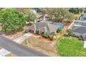 Aerial view of a single-story home with a screened pool, manicured lawn, mature trees, and a red painted garage door at 7741 Merrily Way, Lakeland, FL 33809