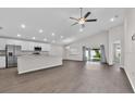 Open-concept living room with modern ceiling fan, stainless steel kitchen appliances, and sliding door access to the yard at 1106 Tropea Ln, Auburndale, FL 33823