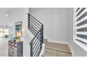 Modern staircase featuring a black metal railing and light wood-look tile steps, illuminated by natural light at 1171 Windjammer Dr, Lakeland, FL 33803