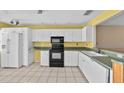 Bright kitchen featuring white cabinets, tile floors, and black appliances at 2173 Castle Pt, Winter Haven, FL 33880