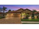 Warm and inviting home with a paver driveway, lush landscaping, and a well-lit exterior at 3926 Aquilla Dr, Lakeland, FL 33810