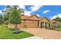 Beautiful home with a well-maintained lawn, paver driveway, and lush landscaping at 3926 Aquilla Dr, Lakeland, FL 33810