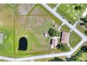 Aerial view of property, outlined in yellow, featuring a pond, surrounded by grassy fields and a home at 4404 Musket Dr, Lakeland, FL 33810