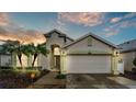 Inviting home exterior at dusk featuring a two-car garage, lush landscaping, and warm lighting at 506 Henley Cir, Davenport, FL 33896
