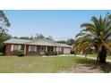 Well-kept brick home with a spacious front yard, mature landscaping, and attached garage at 6131 Doe E Cir, Lakeland, FL 33809