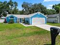 Quaint blue home boasting a well-manicured lawn, landscaping, and a two-car garage at 6810 Palomino Dr, Lakeland, FL 33811