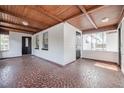 Covered porch with a tile floor, natural wood ceiling, and white brick walls at 1507 Holly Rd, Lakeland, FL 33801