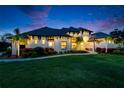 Stunning exterior shot of a modern home with lush landscaping, palm trees, and a beautiful lawn at twilight at 2662 Delphi Hills Ct, Lakeland, FL 33812