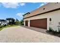 View of the three-car garage and a brick paved driveway of this beautiful home at 2662 Delphi Hills Ct, Lakeland, FL 33812