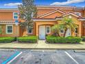Inviting two-story condo with an orange exterior, lush landscaping, and handicap parking at 2683 Corvette Ln, Kissimmee, FL 34746