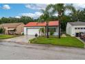 Charming single-story home with a well-manicured lawn, mature palm trees, and a red tiled roof at 409 San Jose Dr, Winter Haven, FL 33884
