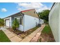 The side exterior with a paved walkway, utility connections, garden bed, and window at 409 San Jose Dr, Winter Haven, FL 33884
