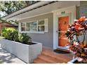 Close-up of the front entrance featuring brick steps, white brick planter, and a vibrant orange door at 618 W Oak Dr, Lakeland, FL 33803