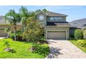 Two-story home featuring lush landscaping, a paver driveway, and a warm, inviting facade at 843 Christina Chase Dr, Lakeland, FL 33813