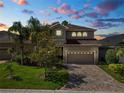Two-story home featuring lush landscaping, a paver driveway, and a warm, inviting facade at 843 Christina Chase Dr, Lakeland, FL 33813