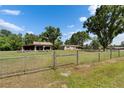 Exterior front yard view of home with metal gate, grass, and mature trees at 2145 Limedale Rd, Lakeland, FL 33809