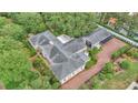 Detailed aerial view of the home with lush gardens, brick driveways, and mature trees surrounding it at 323 E Belvedere St, Lakeland, FL 33803