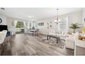 Bright living room with wood-style floors, a modern chandelier, and lots of natural light at 4303 Moon Shadow Loop, Mulberry, FL 33860