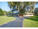 Inviting single-story home featuring a large front yard, mature trees and an orange front door at 5121 Shady Oak S Dr, Lakeland, FL 33810