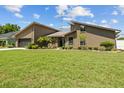 Well-maintained single-Gathering home with a lush green lawn, mature trees, and an attached garage at 5519 Club W Hl, Lakeland, FL 33812