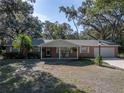 Inviting single-Gathering home featuring a covered porch with rocking chairs, complemented by a manicured lawn and mature trees at 5624 Laurel Oak Dr, Lakeland, FL 33811