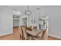 Bright dining room boasts wood floors, contemporary light fixture, and seamless access to other living spaces at 601 Pintail Cir, Auburndale, FL 33823