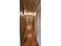 A long, narrow hallway with wooden floors, doors, and framed art at 629 W Williams St, Lakeland, FL 33805
