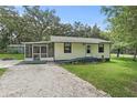 Cozy single-story home featuring a screened-in porch, gravel driveway, and green lawn at 633 Glenda St, Lakeland, FL 33805