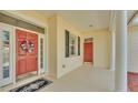 Covered front porch featuring a red front door, black accents, and tile flooring at 2025 Viewpoint Landings Rd, Lakeland, FL 33810