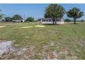 Neutral colored single-story home with black shutters surrounded by a large lawn at 246 Quail Run, Frostproof, FL 33843