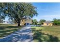 Spacious driveway leading to a three-story yellow home with a detached garage and mature trees at 3020 Crews Lake Dr, Lakeland, FL 33813