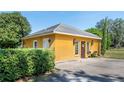 Exterior of a detached garage with a door, sconces, a small table and manicured hedges at 3020 Crews Lake Dr, Lakeland, FL 33813